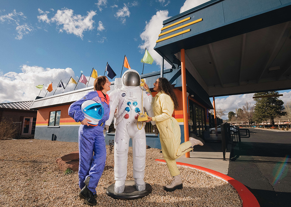 a woman standing next to a statue of a man wearing a space suit