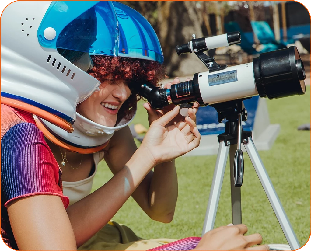 a woman wearing a helmet looking through a telescope