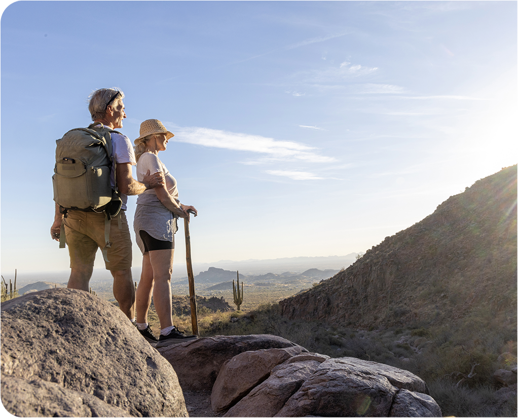 a man and woman standing on a rock with a stick