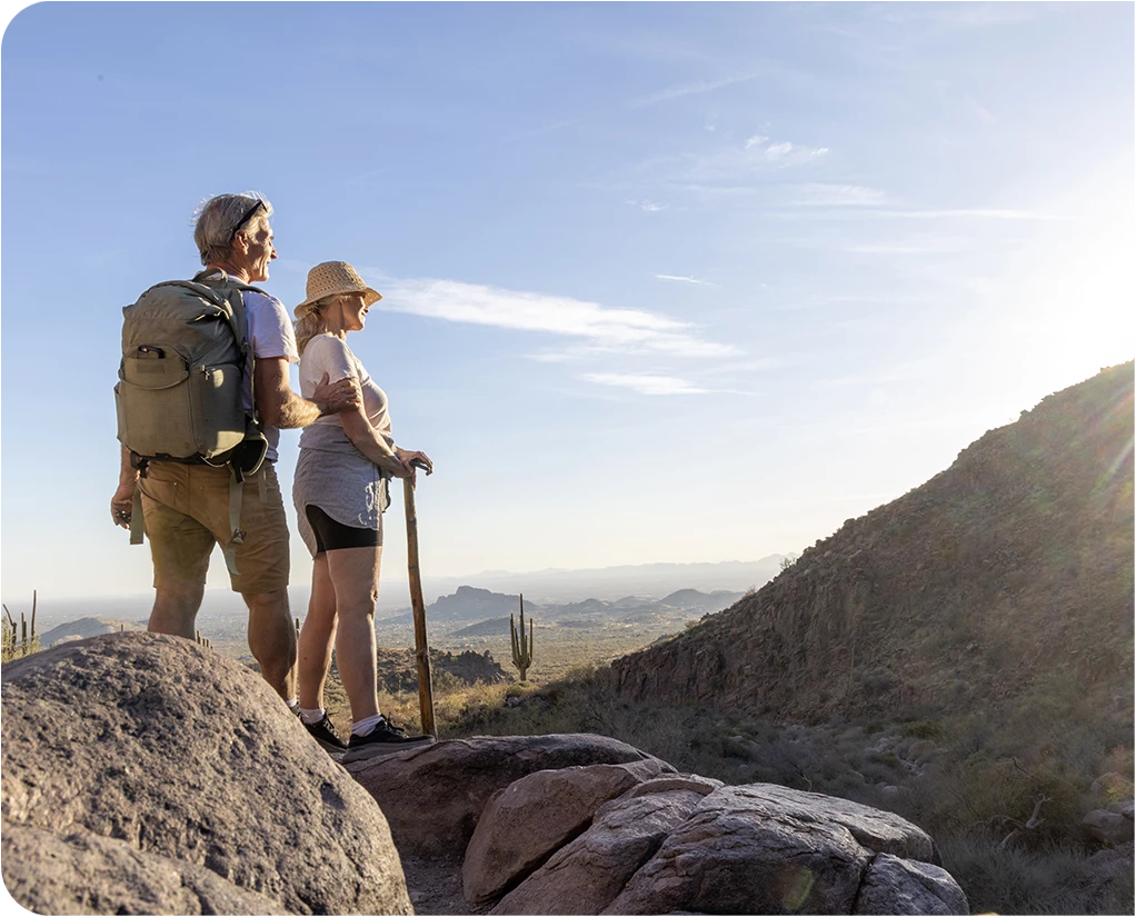 a man and woman standing on a rock with a stick