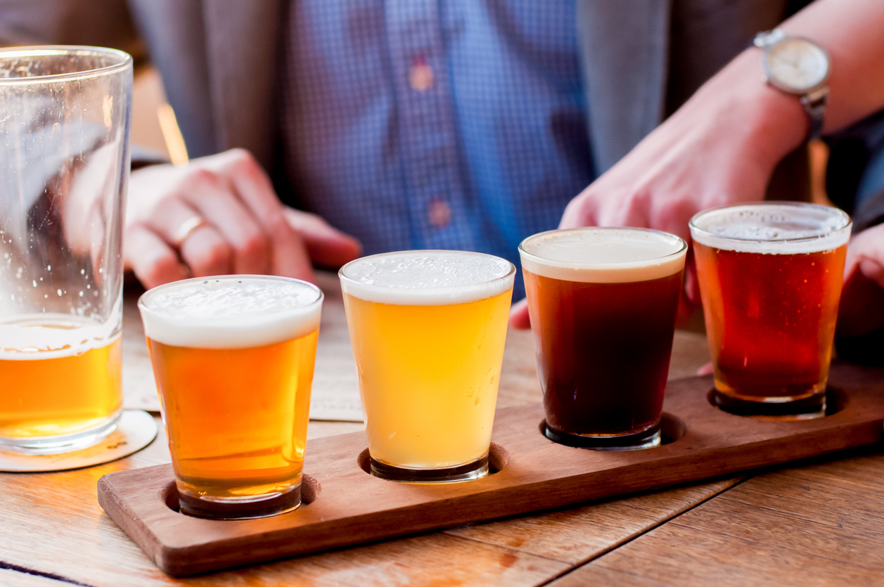 a group of glasses of beer on a wooden tray