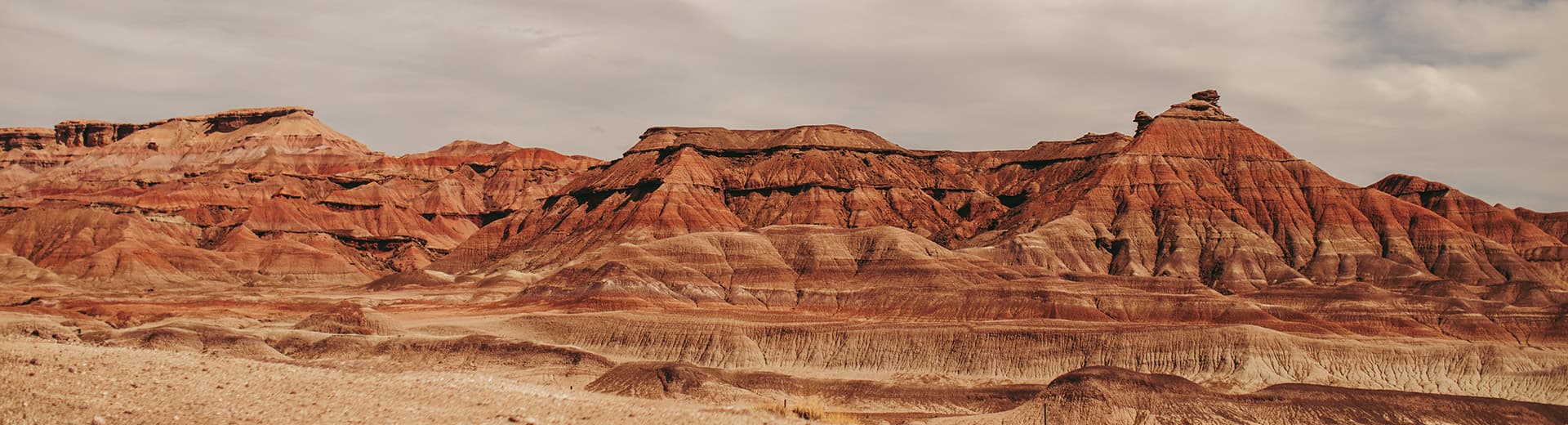 a large red mountain with a cloudy sky