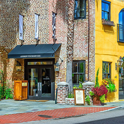 a building with a black awning and a yellow building with flowers