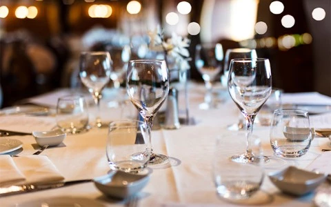 A formal dining table set with white tablecloth, wine glasses, and dinnerware.