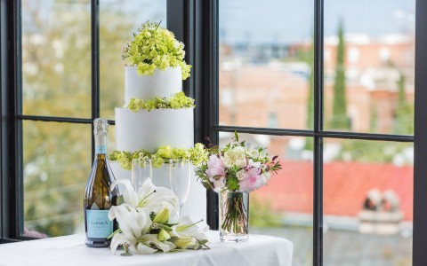 a table in front of a window with a wedding cake