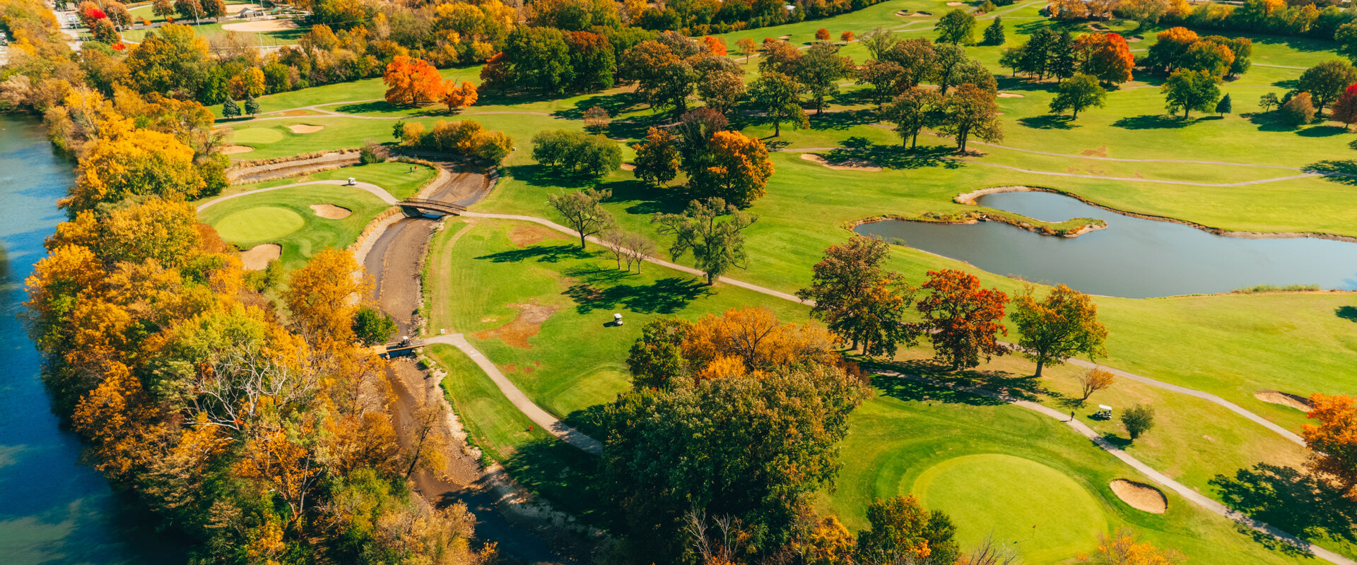 a golf course with trees and a river