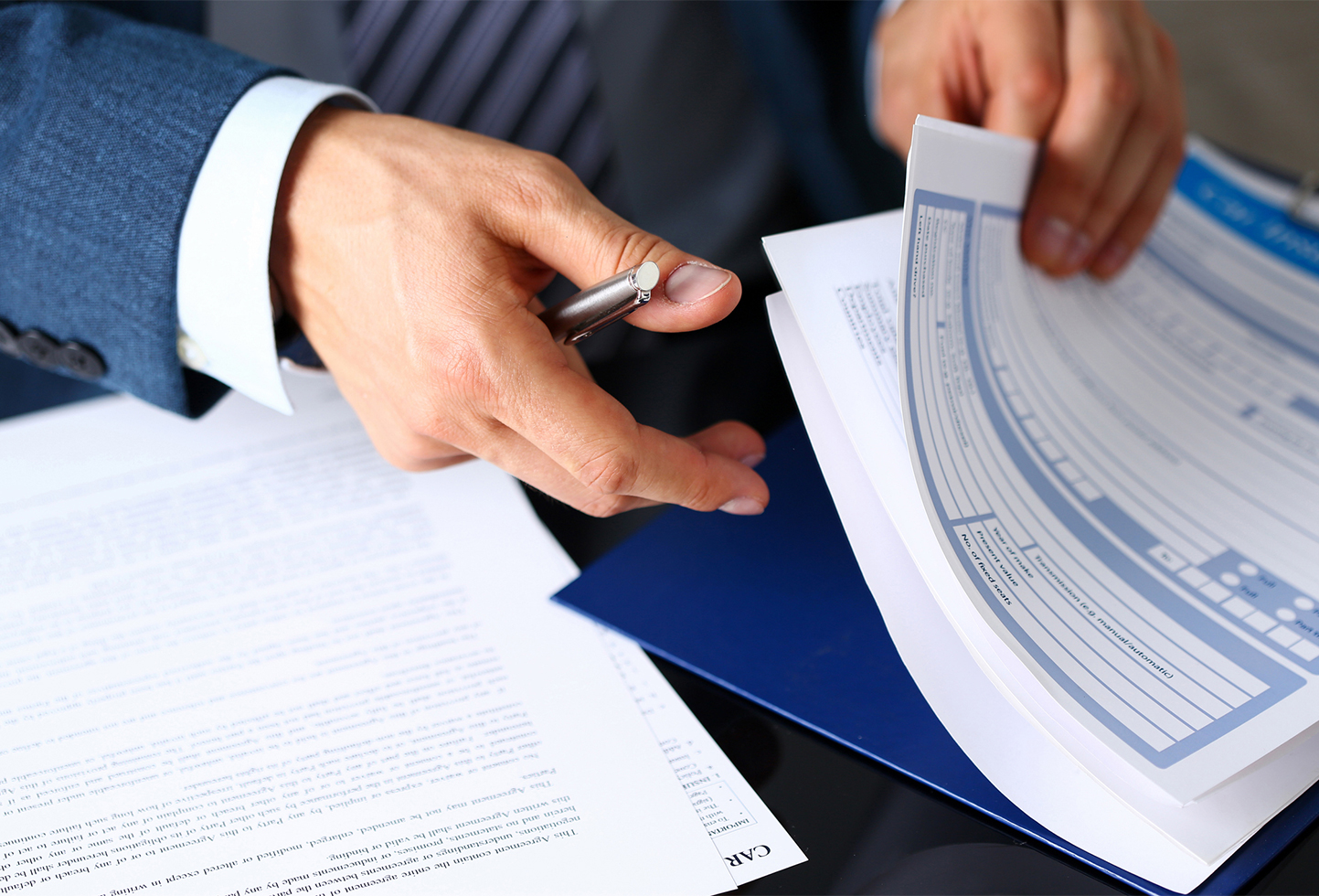 a person holding a pen over papers
