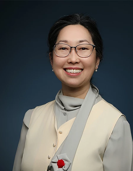 a woman wearing glasses and a beige vest