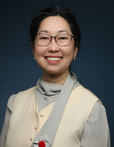 a woman wearing glasses and a beige jacket