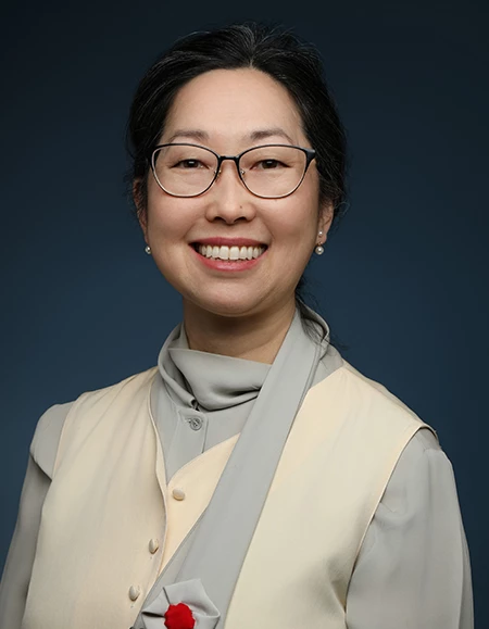 a woman wearing glasses and a beige jacket