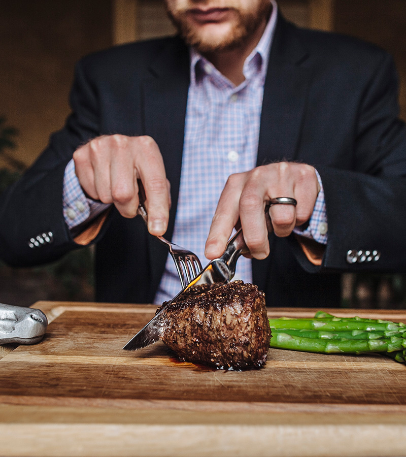 man cutting a steak with asparagus next to it