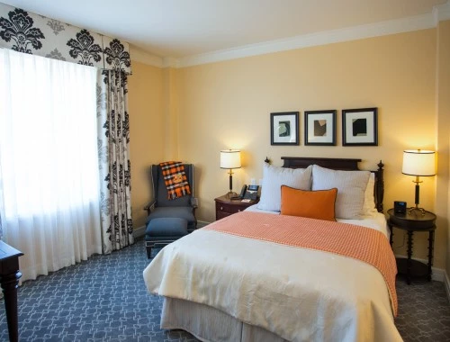 bed with orange accents and black and white curtains
