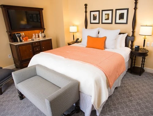 deluxe king bedroom with a grey couch and chair with a cabinet and two night stands