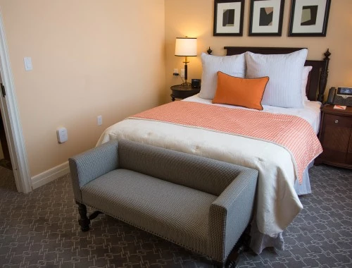 executive suite bedroom with orange accents and grey couch
