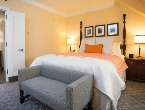 king bed with orange accents and a grey sofa