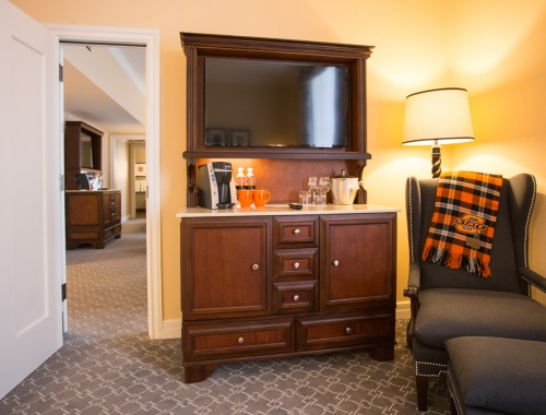 view of hotel room with chair and cabinet with coffee maker and tv