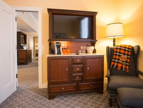 view of hotel room with chair and cabinet with coffee maker and tv