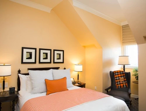 bedroom with yellow walls and orange accents on the bed