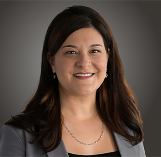 a woman with long brown hair wearing a grey blazer