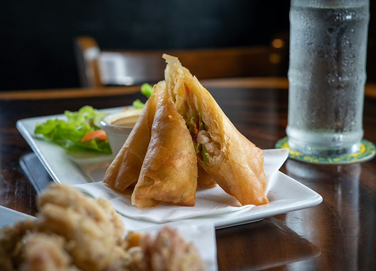 a plate of fried spring rolls and a glass of water