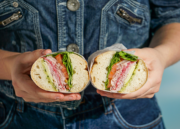 a person holding sandwiches in their hands