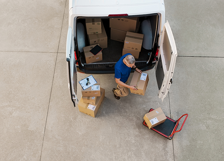 a man carrying boxes in the back of a van