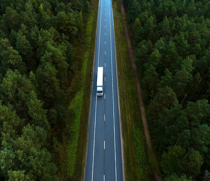 a truck on a road surrounded by trees