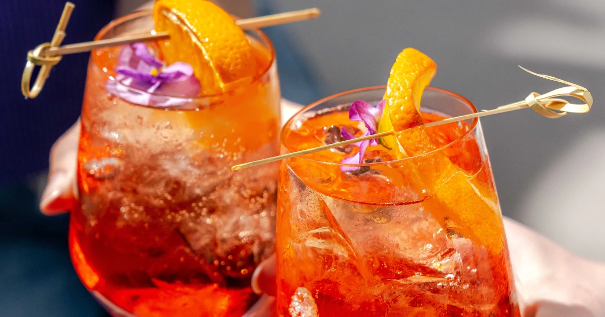 two glasses of orange drinks with a flower and a straw
