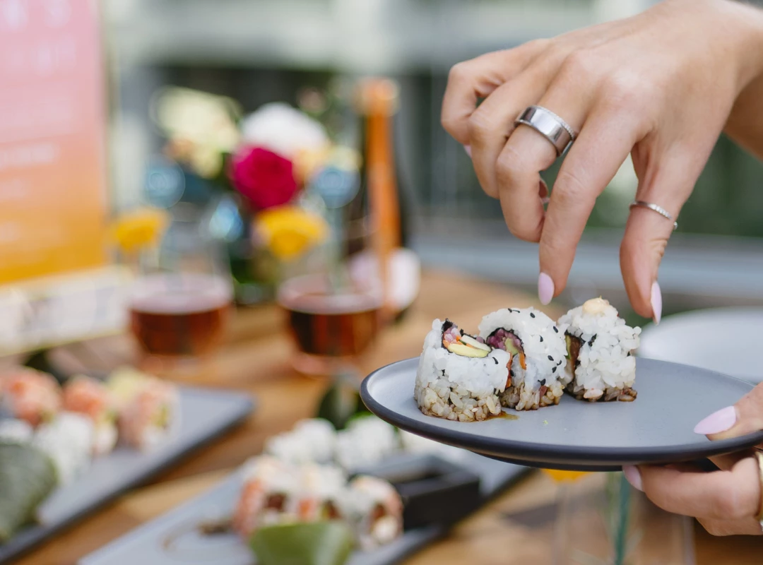 a hand holding a plate of sushi