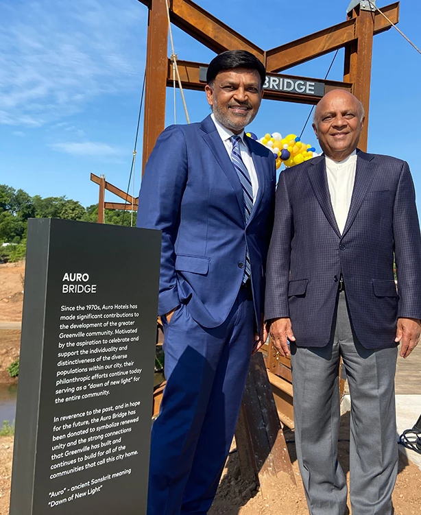 a couple of men in suits standing in front of a sign