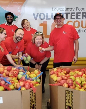 a group of people standing next to boxes of fruit