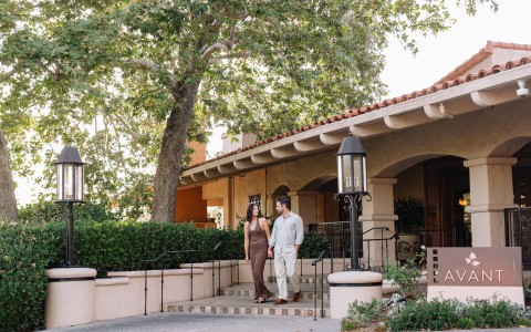 a man and woman holding hands walking on a porch of a house