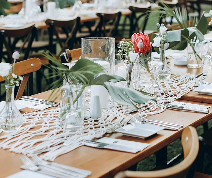 wood table with green plants, net place mats, and small plates with silverware