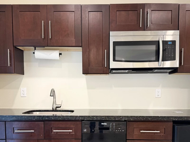 a kitchen with dark brown cabinets and a microwave