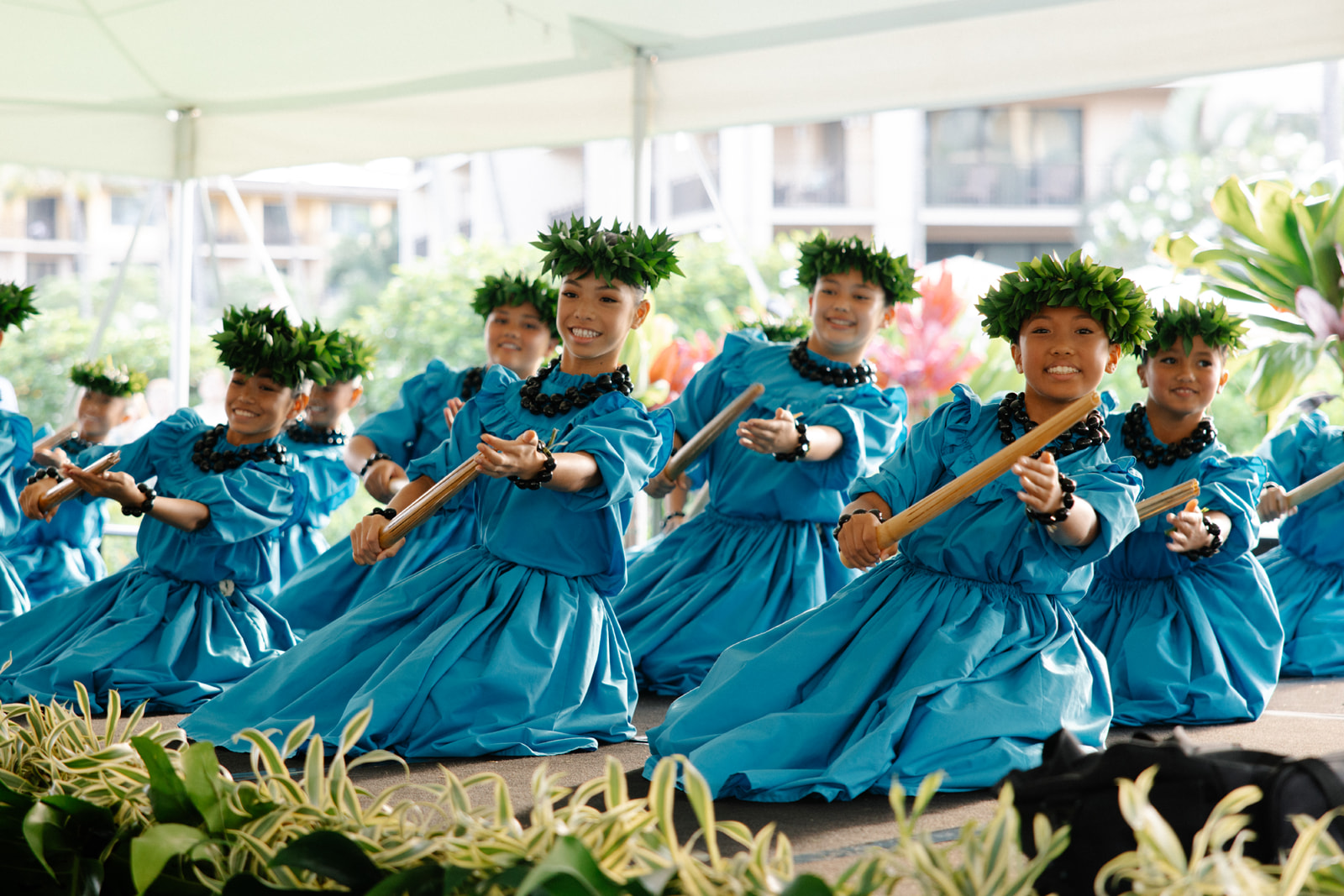 a group of women in blue dresses with green leaves on their head