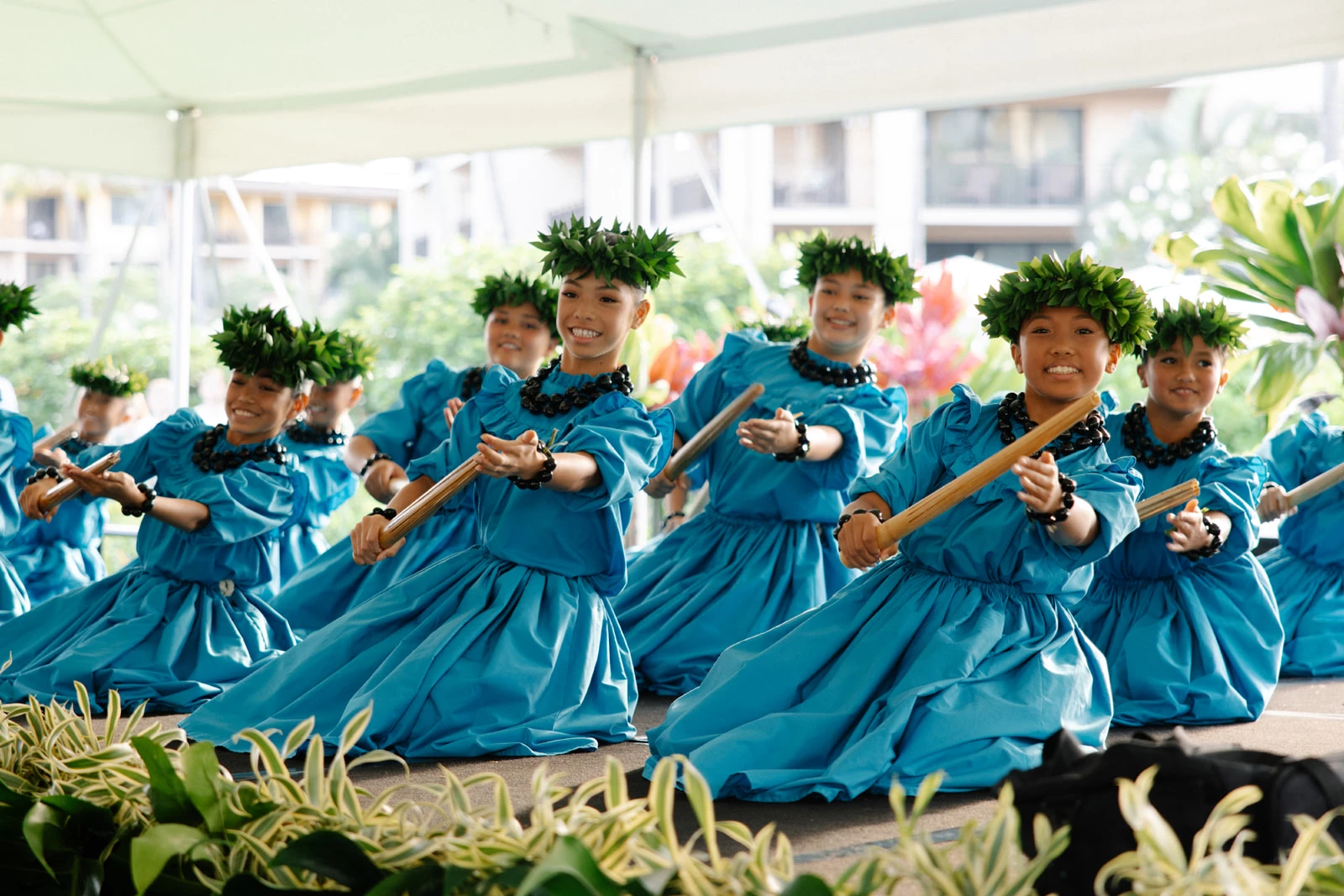 a group of women in blue dresses with green leaves on their head