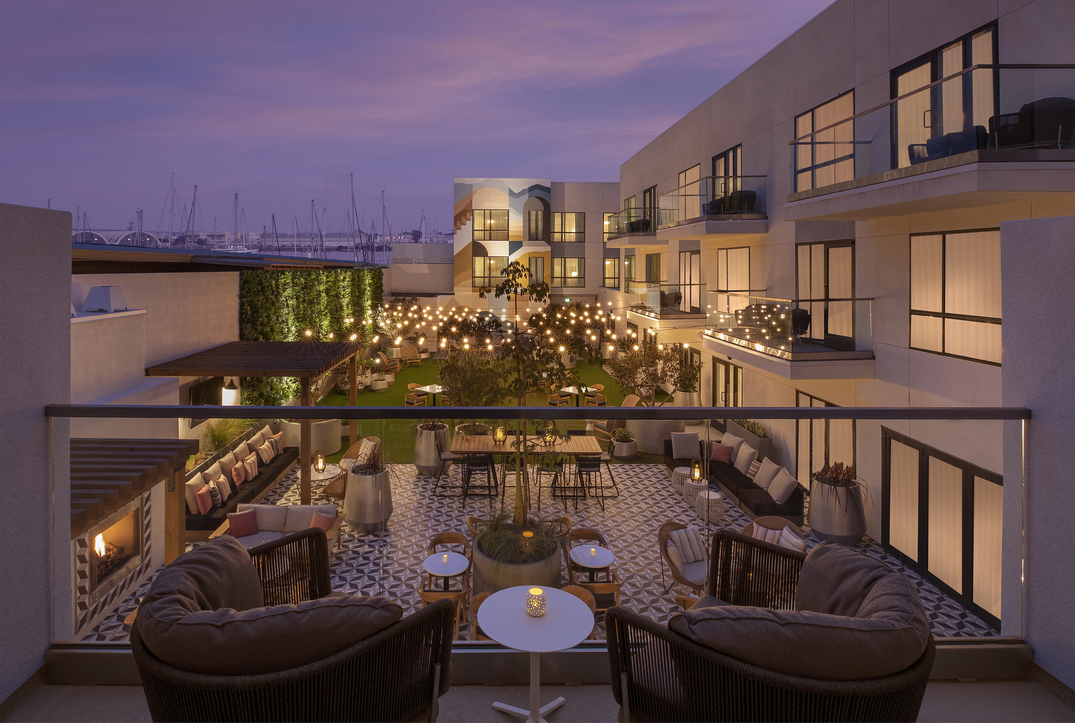 a patio with chairs and tables and a tree in front of a building