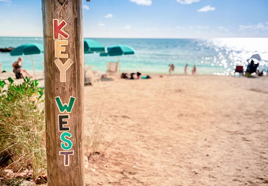close up of a key west sign on a beach