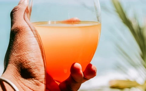 first person perspective of a hand holding an orange drink