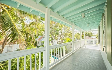 a porch with mint green ceiling and a view of palm trees outside