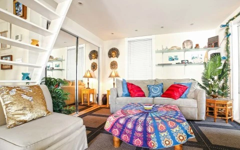 turtle house living room with beige couches and colorful pillows and a tapestry on the coffee table
