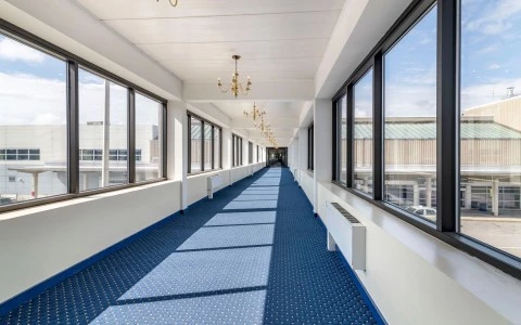 a long hallway with windows and a chandelier