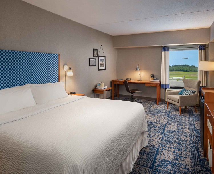 corner view of a queen bedroom of a hotel in gray accents