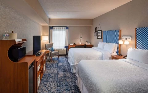 view of 2 double bed guest accommodations with sitting area and desk