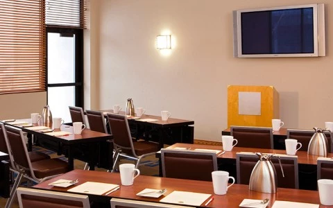 meeting room with rows of tables with a podium and tv in front of the room 