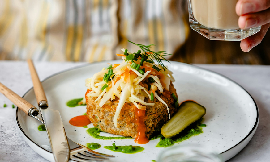 a plate of food with a pickle and a glass of liquid