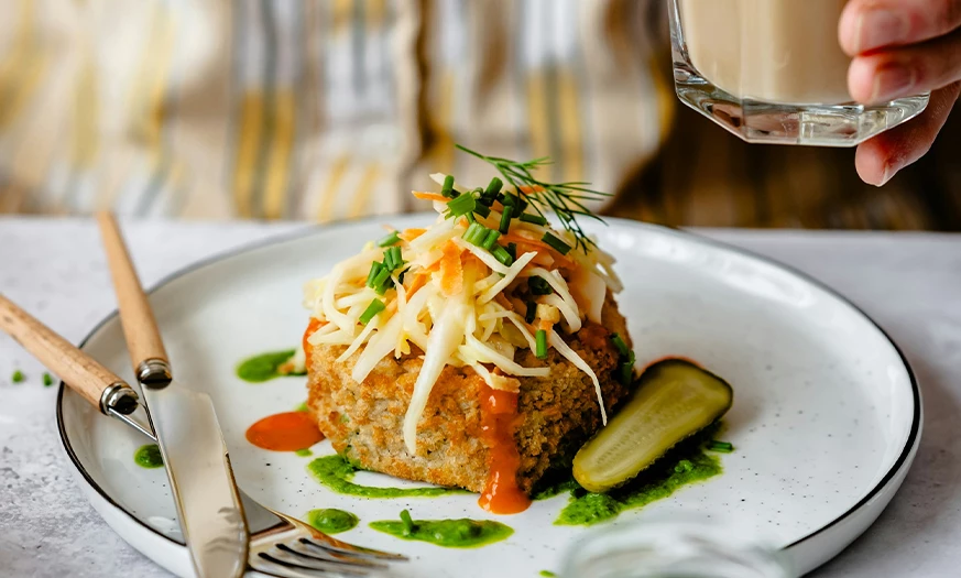 a plate of food with a pickle and a glass of liquid