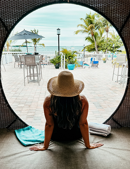 a woman sitting on a patio looking out of a round window