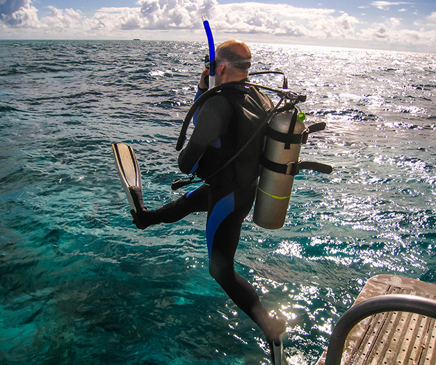 a man in a scuba suit jumping off a boat