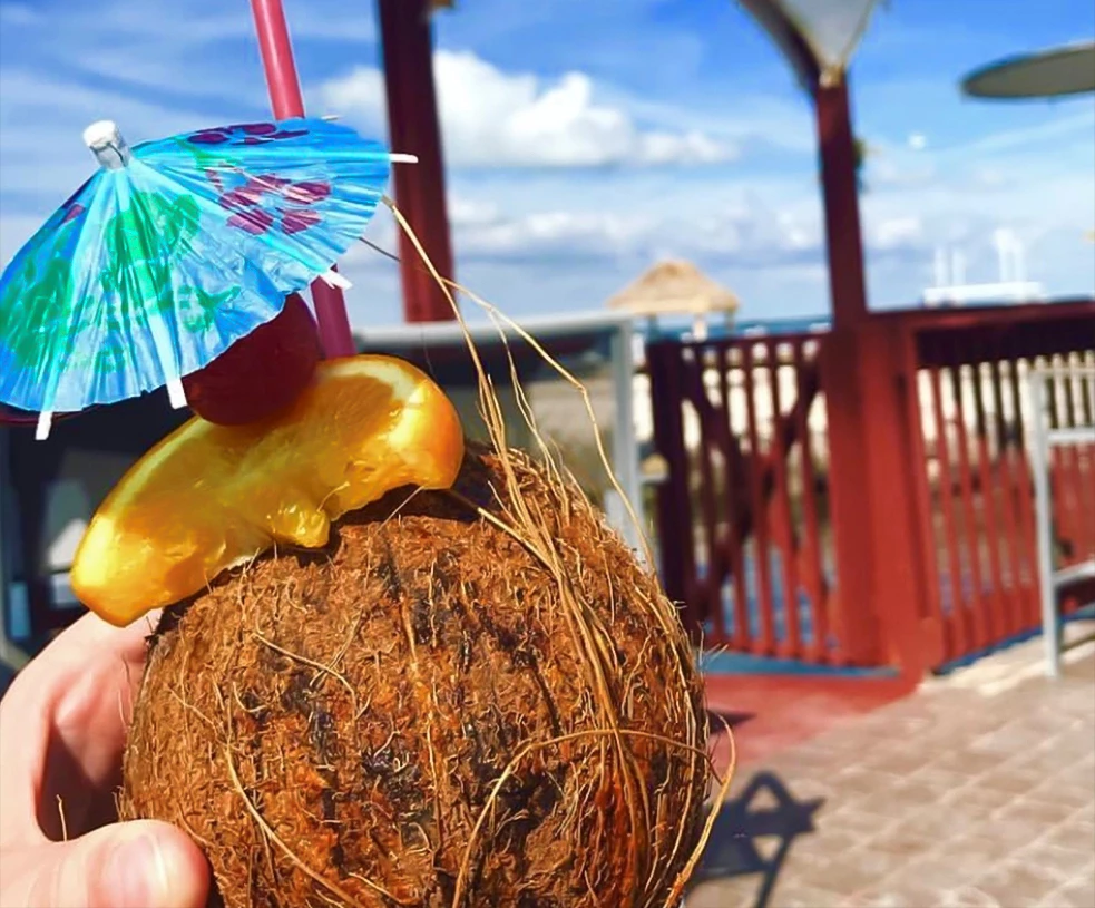 a coconut with an umbrella and an orange slice on top